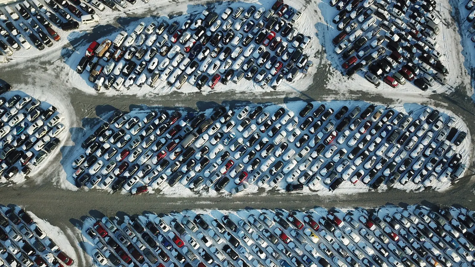 Aerial view of rows of parked cars with snow between them