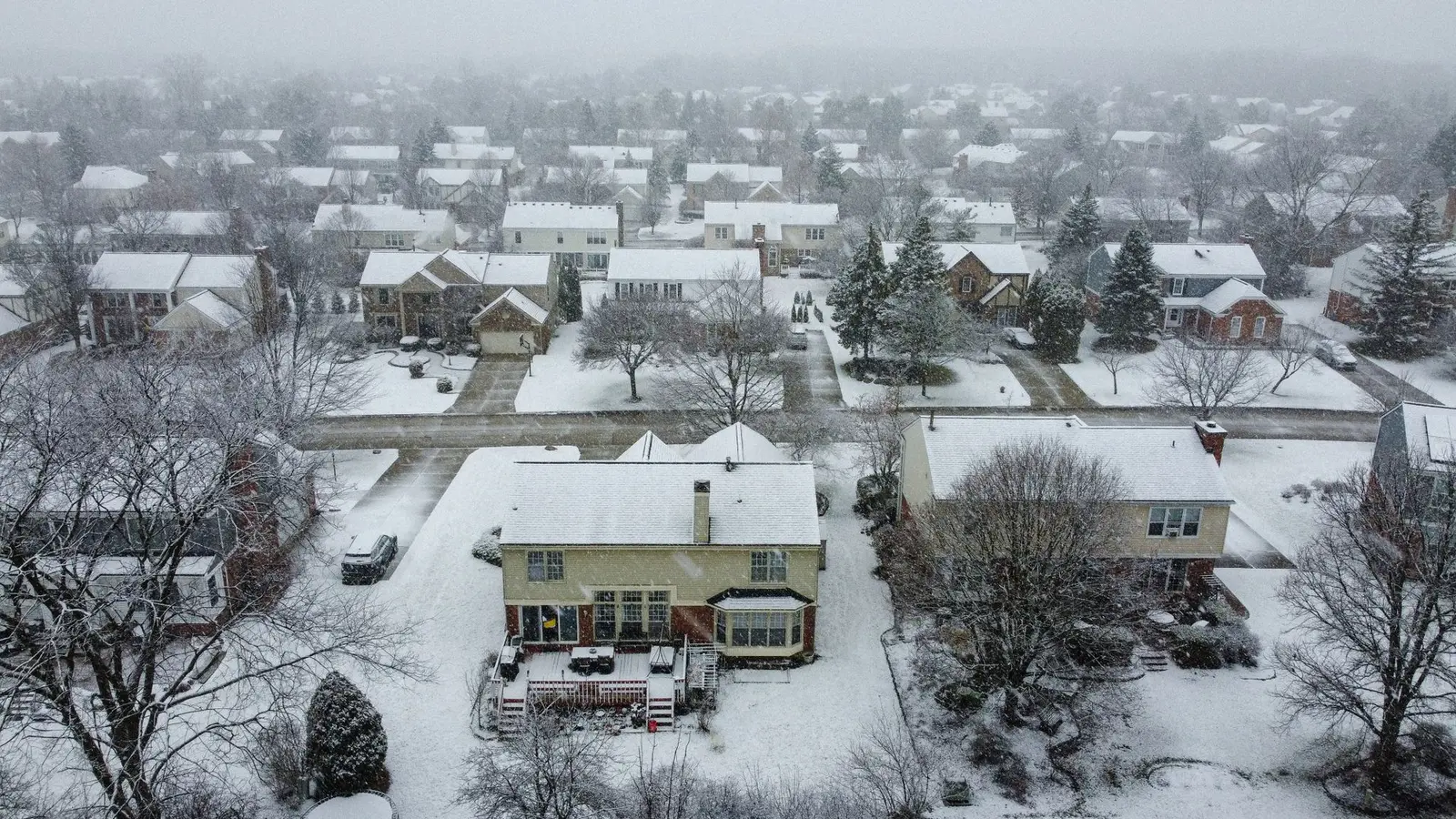 Aerial view of snow-covered homes and yards in a subdivision