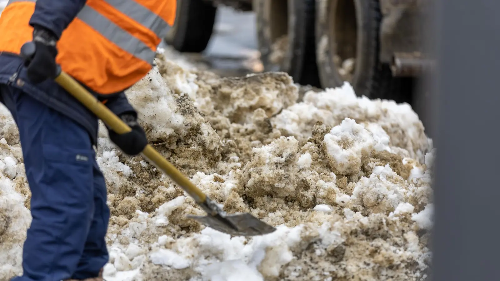 Worker shoveling heavy, slushy snow beside a curb