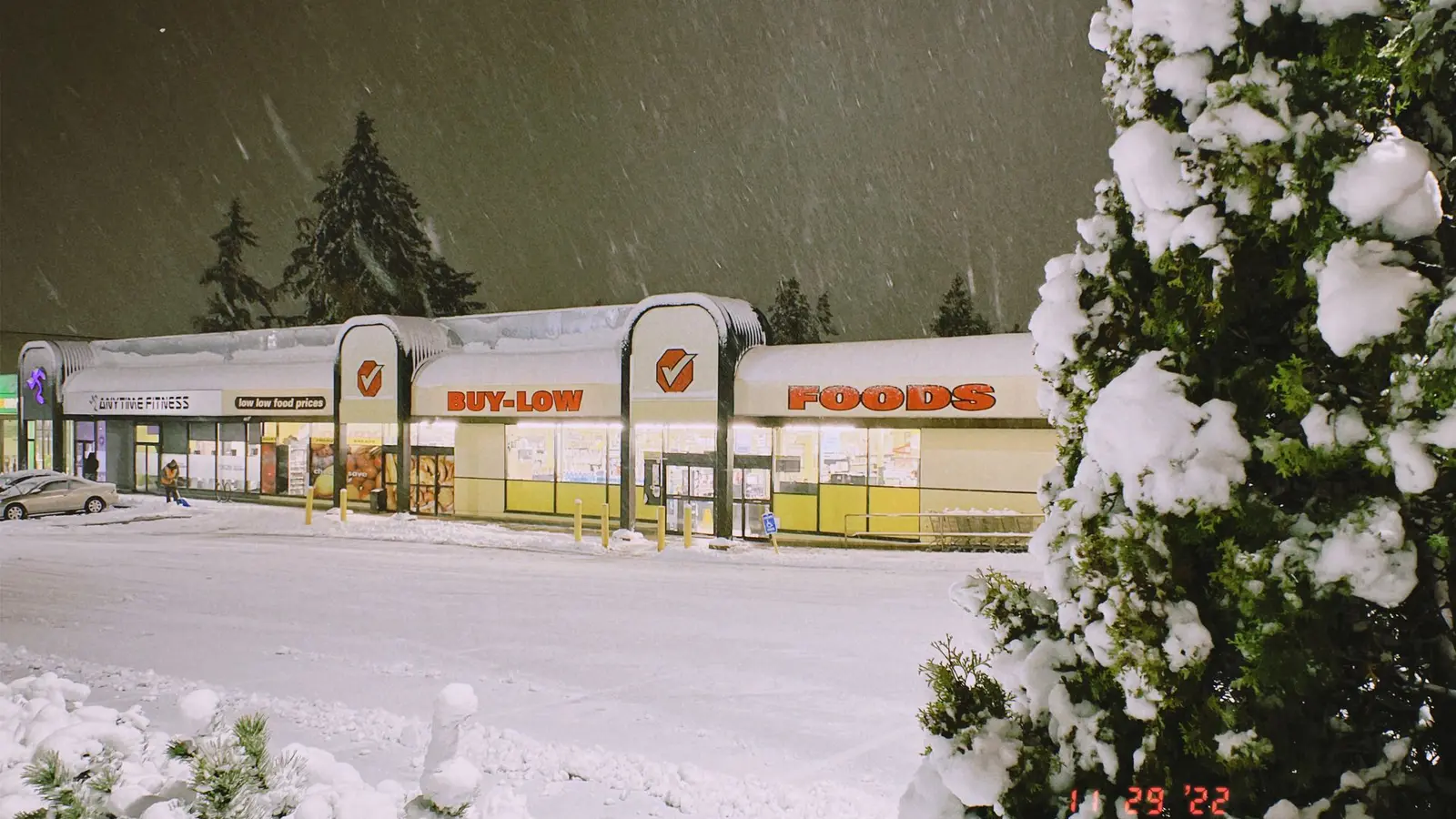 Snow-covered parking lot outside a grocery store at night